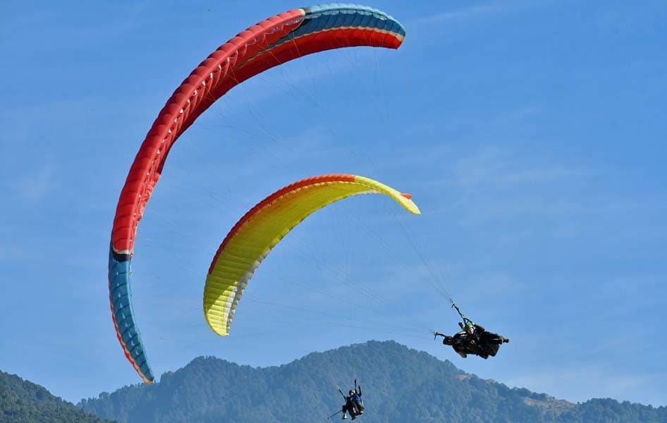 Two paragliders soaring over the mountains above Bir Billing