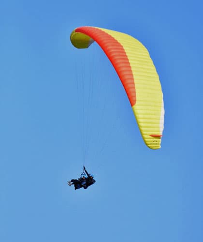 A single paraglider canopy against a clear blue sky