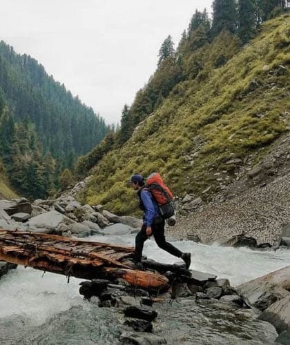 A trekker crossing a stream on the Rajgundha trek
